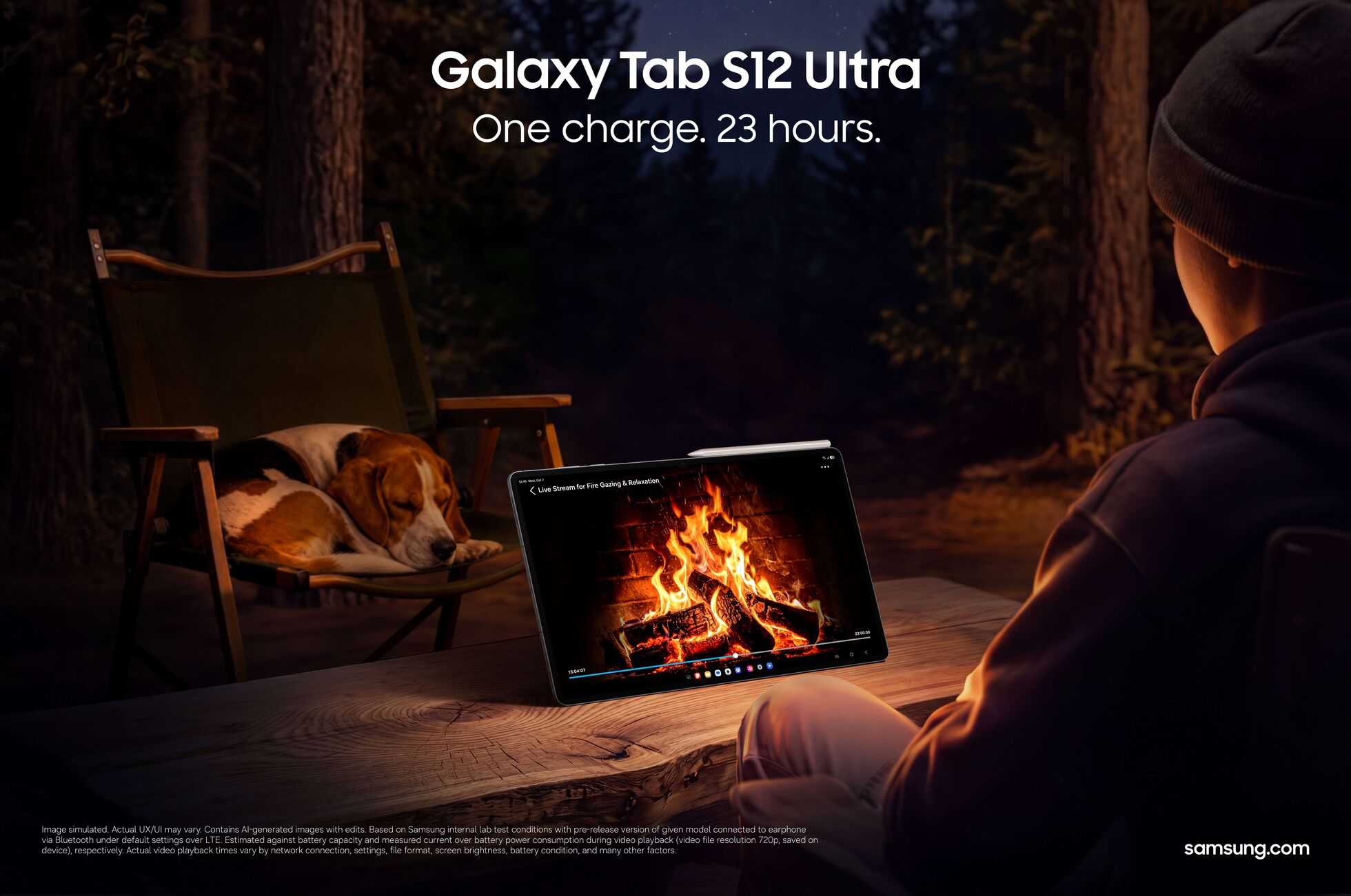 A night-time campsite in the woods: someone in a beanie, seen from behind, watches a tablet on the table playing a campfire scene, with a dog on a folding chair beside them; text: Galaxy Tab S12 Ultra, One charge. 23 hours.